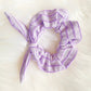 Light purple scrunchie with a bow sits on a faux fur rug